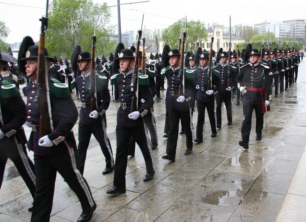 A precise and disciplined military parade featuring Norwegian soldiers in traditional uniforms with green accents, marching in formation during the Norwegian Military Tattoo. The image captures the ceremonial display of military tradition and pageantry unique to this event.