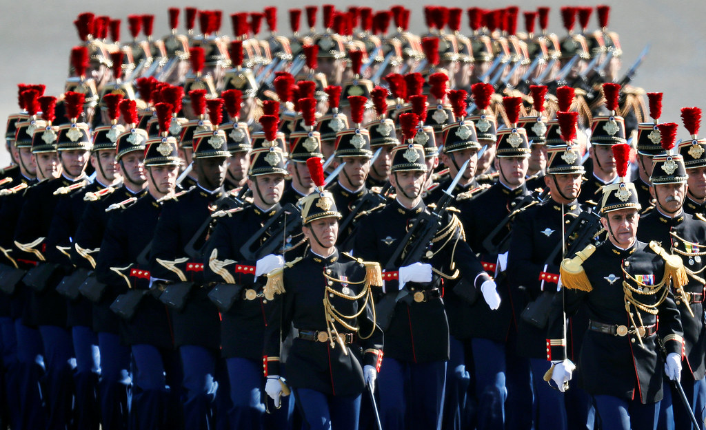 The French Republican Guard Band, a famous military band, marching in perfect formation during a parade, dressed in ornate blue uniforms with gold accents and tall plumed hats, showcasing their precision and discipline.