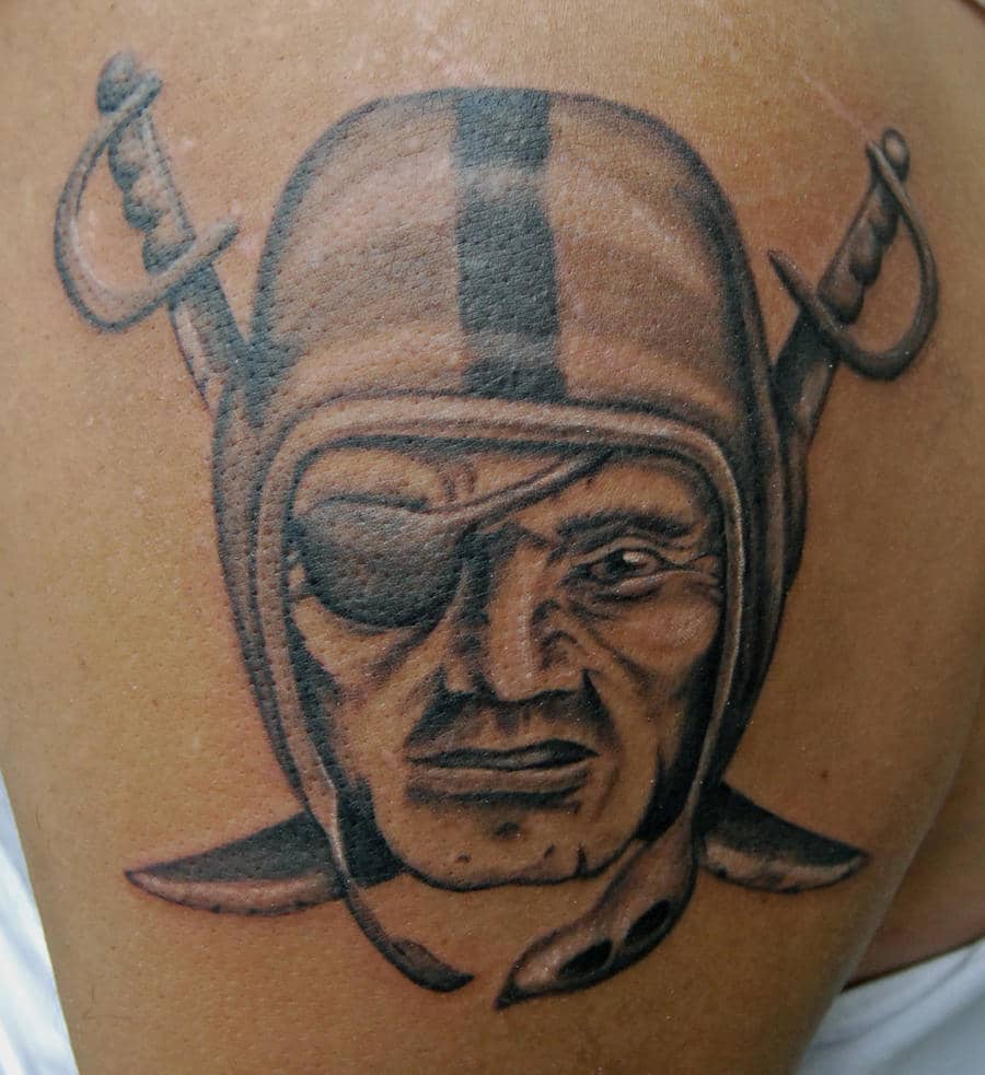 A bold special forces tattoo featuring the iconic face of a soldier with a helmet and an eyepatch, crossed by two swords behind. The detailed black and gray shading emphasizes the stern expression, symbolizing bravery, toughness, and a warrior spirit associated with special forces units.