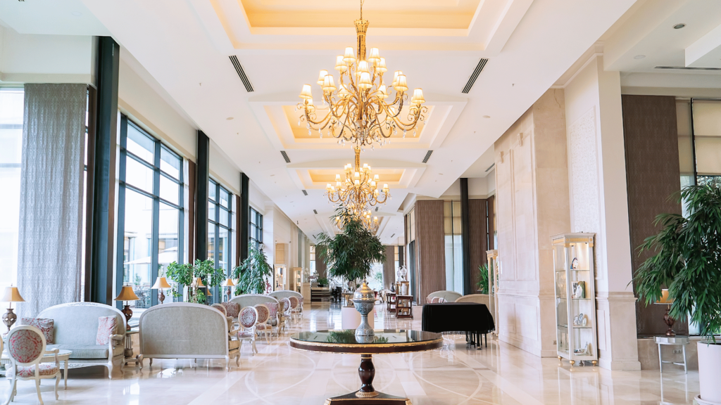 Elegant hotel lobby in Edinburgh with chandeliers, cream seating, large windows, and polished marble floors. Ideal for travelers seeking affordable luxury.