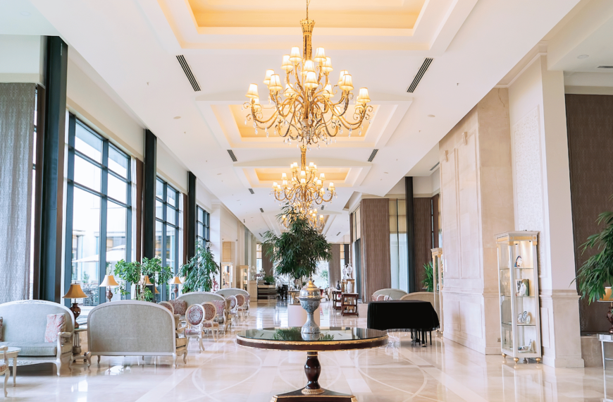 Elegant hotel lobby in Edinburgh with chandeliers, cream seating, large windows, and polished marble floors. Ideal for travelers seeking affordable luxury.