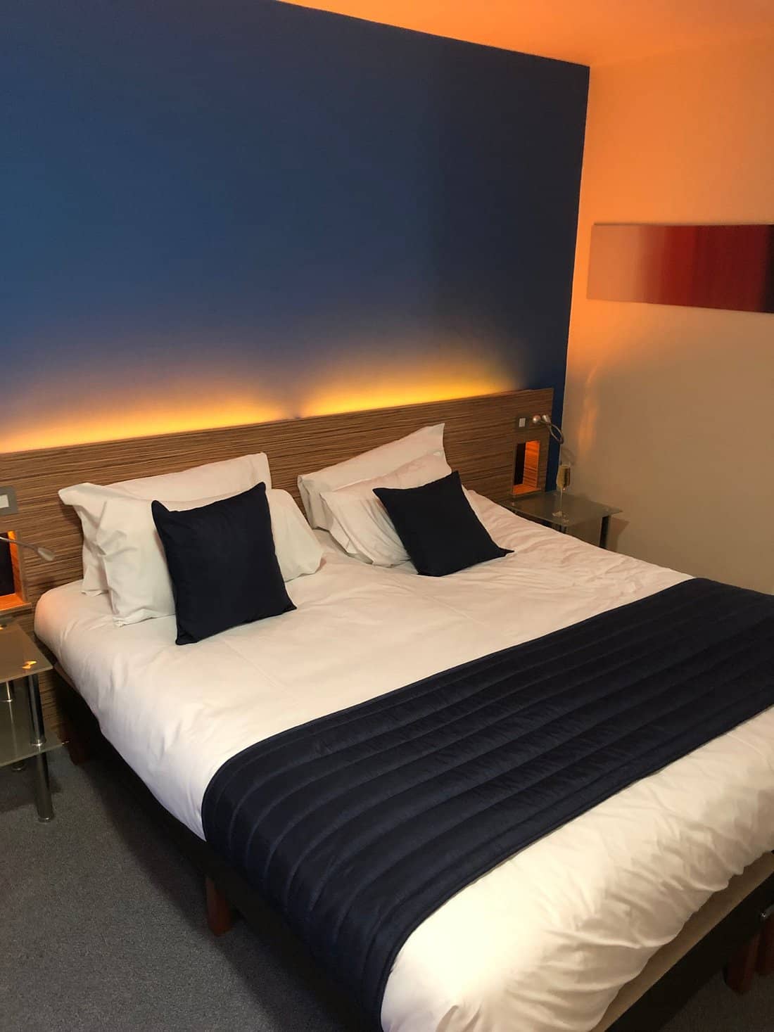 Cozy guest room at Britannia Edinburgh Hotel featuring a double bed with navy blue accents warm lighting and modern decor providing a comfortable and inviting atmosphere for visitors