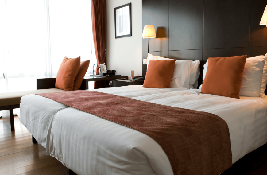 Cozy double room in a budget-friendly Halifax hotel, featuring a neat, wooden decor, soft white linens, and warm-toned pillows for a welcoming feel.