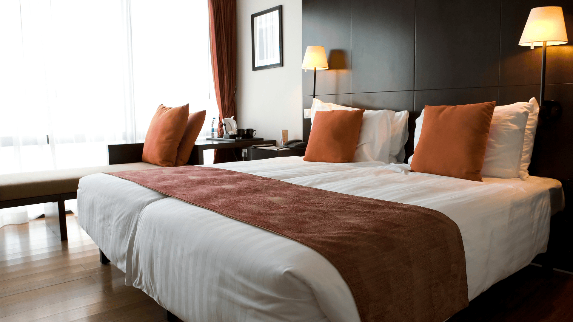 Cozy double room in a budget-friendly Halifax hotel, featuring a neat, wooden decor, soft white linens, and warm-toned pillows for a welcoming feel.