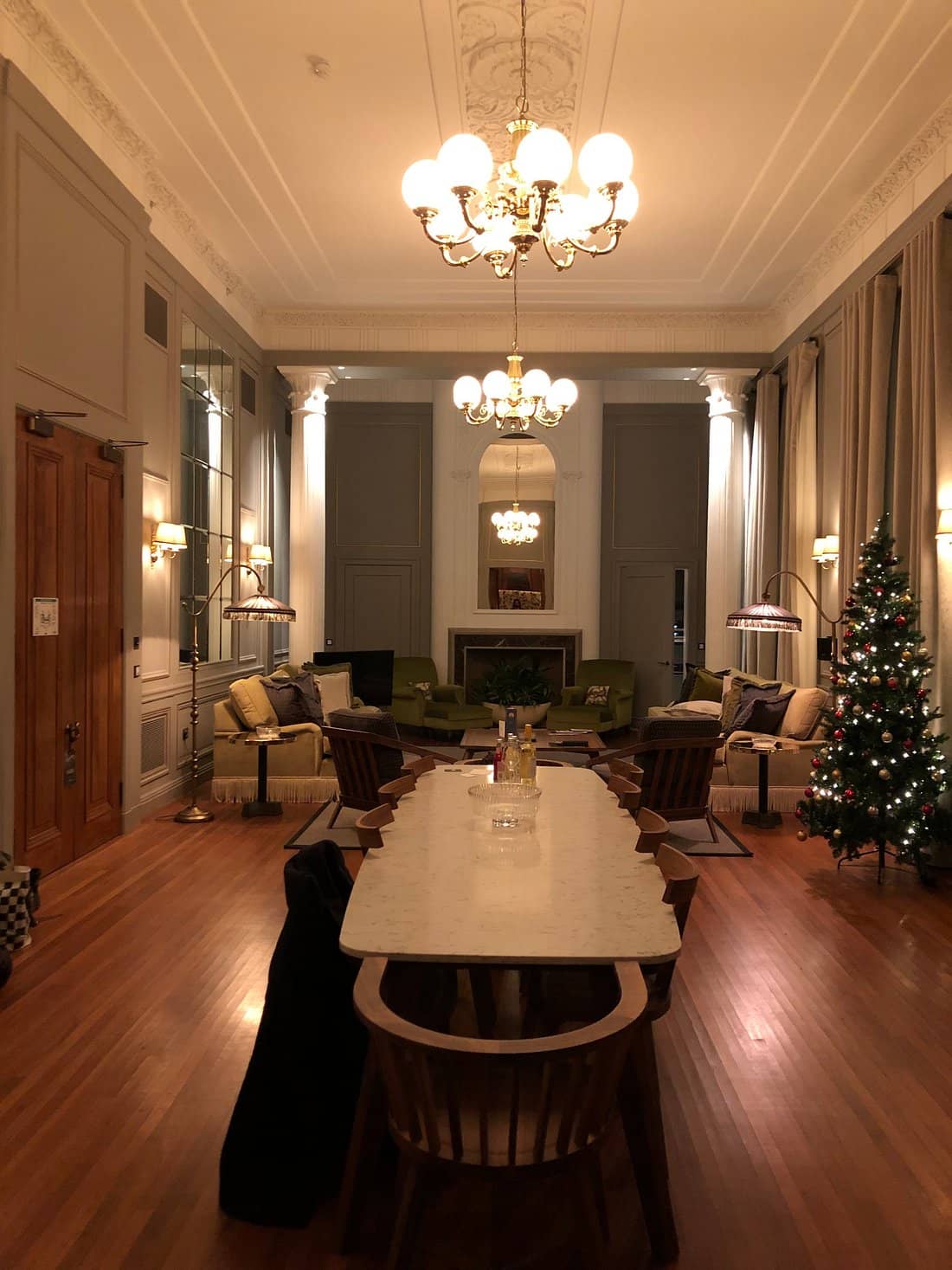 A sophisticated room at Cheval The Edinburgh Grand with a long dining table plush seating chandeliers and a Christmas tree creating an elegant and cozy atmosphere