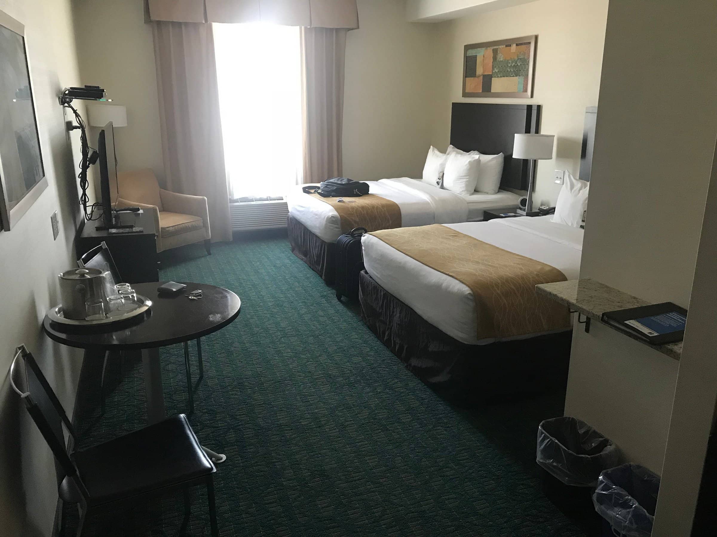 Double room at Comfort Hotel Bayers Lake with two queen beds a small table chairs and a wall-mounted TV Natural light filters through a curtained window