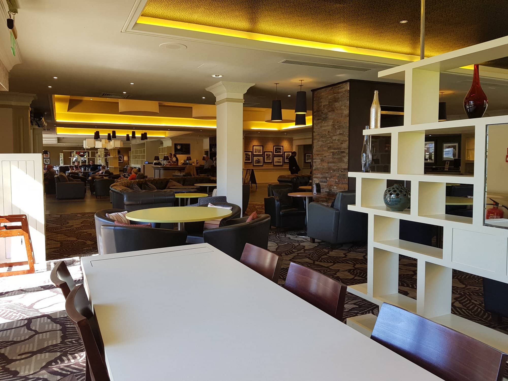 A spacious lounge at DoubleTree by Hilton Edinburgh Airport with modern furniture cozy seating areas warm lighting and an inviting atmosphere for guests to relax and dine