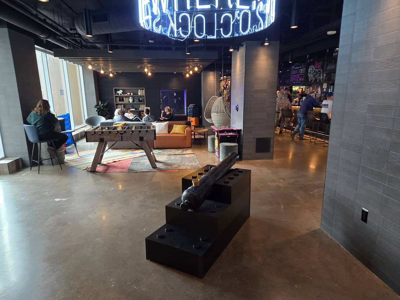 Lounge area at Moxy Halifax Downtown with modern decor cozy seating a foosball table and a bar in the background