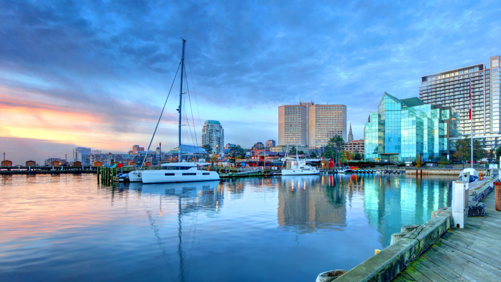 Halifax waterfront at sunset with modern buildings and yachts docked along the boardwalk, highlighting top-rated hotels.