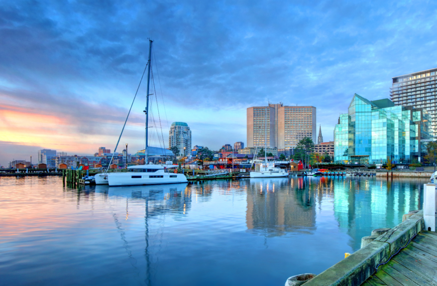 Halifax waterfront at sunset with modern buildings and yachts docked along the boardwalk, highlighting top-rated hotels.