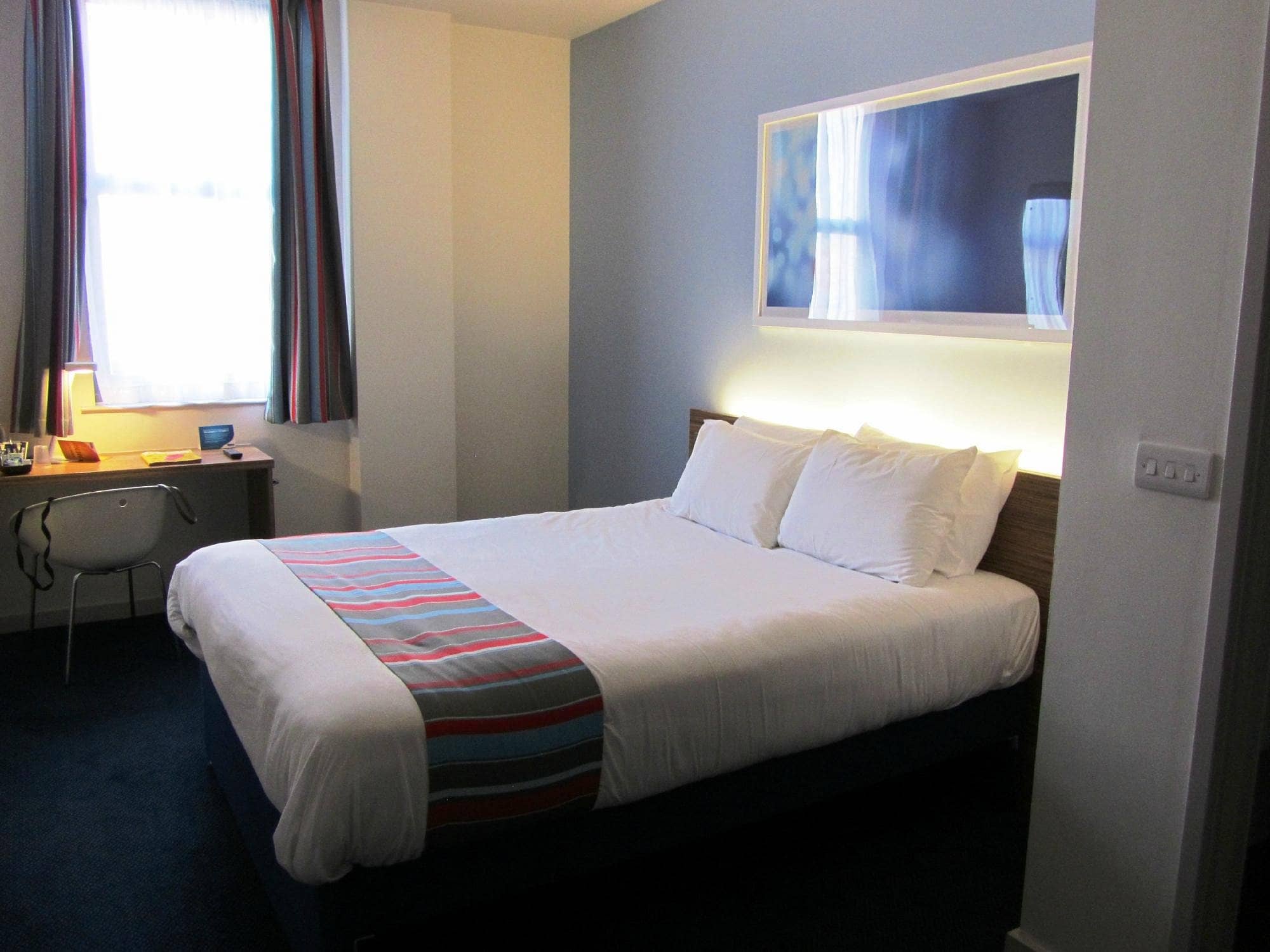  A cozy guest room at Travelodge Edinburgh Central Queen Street featuring a comfortable double bed a small work desk and modern decor providing a budget-friendly stay in the city center