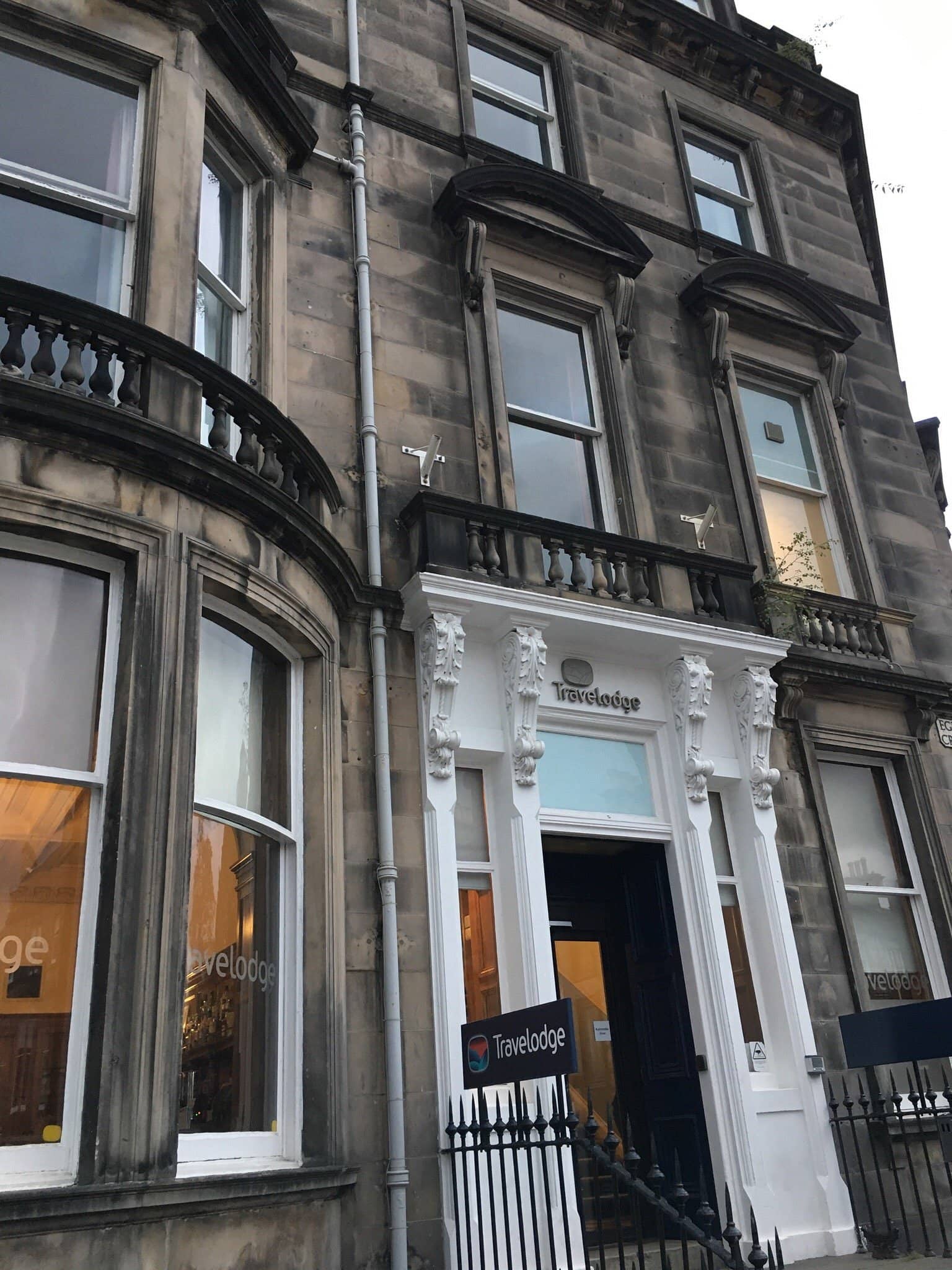 Exterior of Travelodge Edinburgh Haymarket Hotel housed in a traditional stone building with classic bay windows and ornate details offering budget-friendly accommodations near Haymarket Station