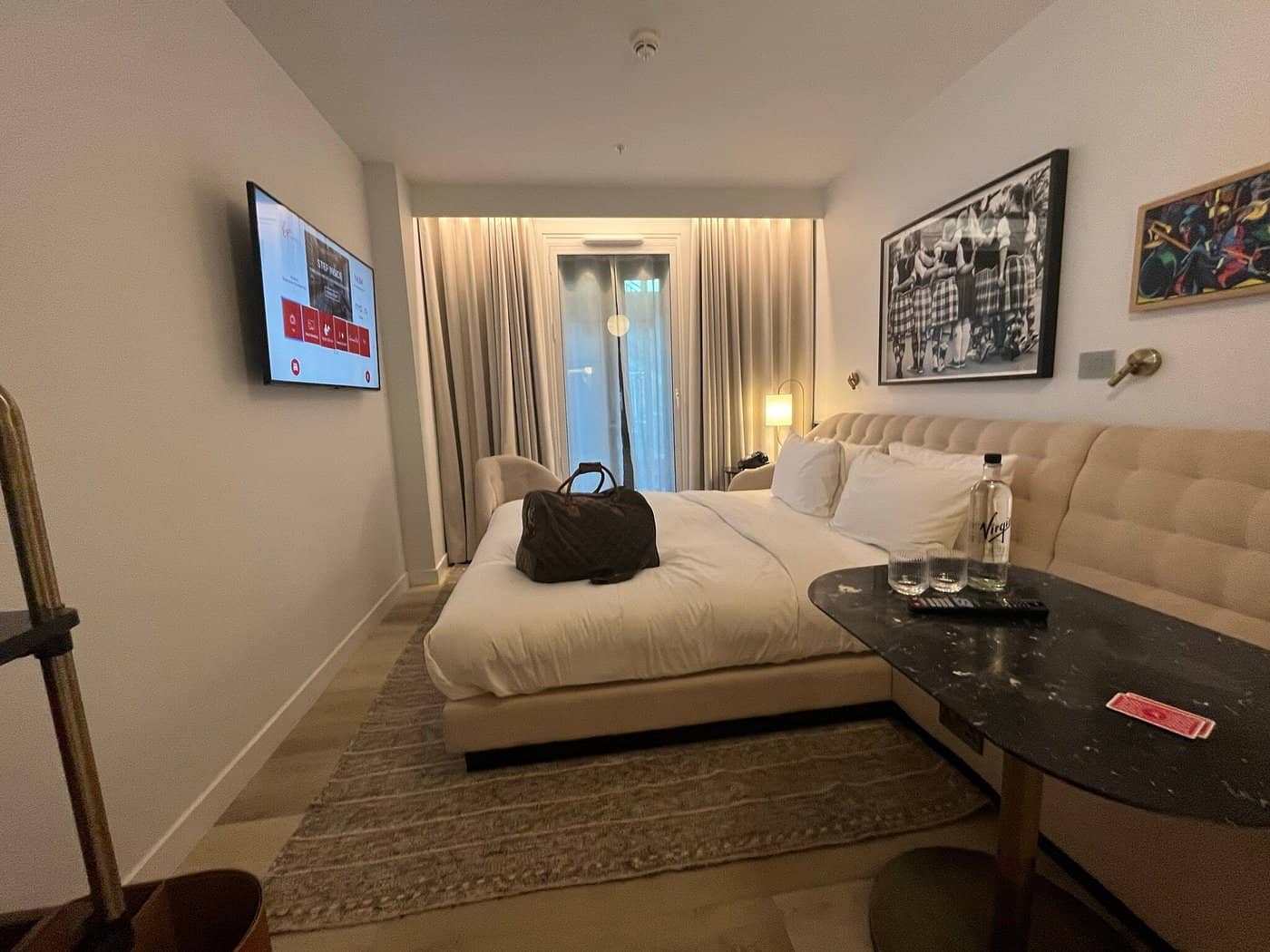 A stylish guest room at Virgin Hotels Edinburgh featuring a cozy double bed wall-mounted TV modern decor and a private balcony offering a luxurious and comfortable stay in the city center