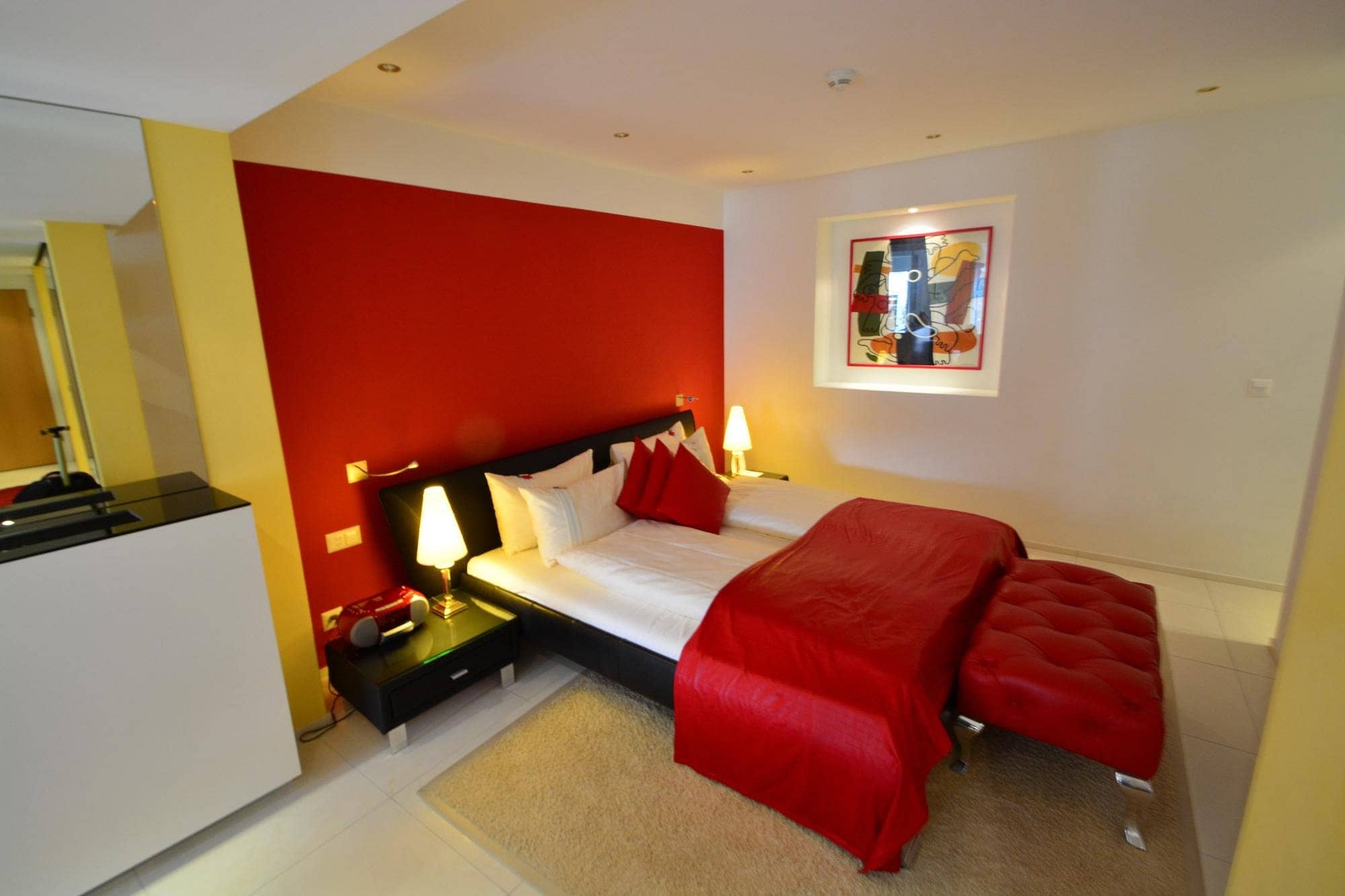 Vibrant room at Gaia Hotel Basel with a bold red accent wall cozy bed matching red decor and modern artwork