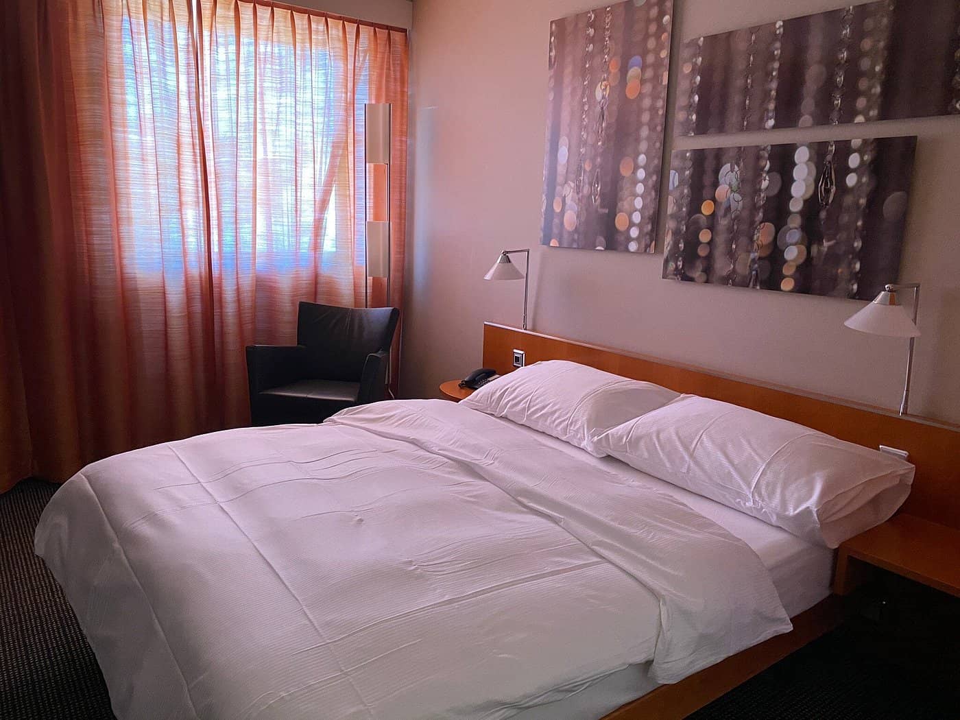 Comfortable room at Hotel Metropol Basel featuring a neatly made bed modern decor and large windows with natural light