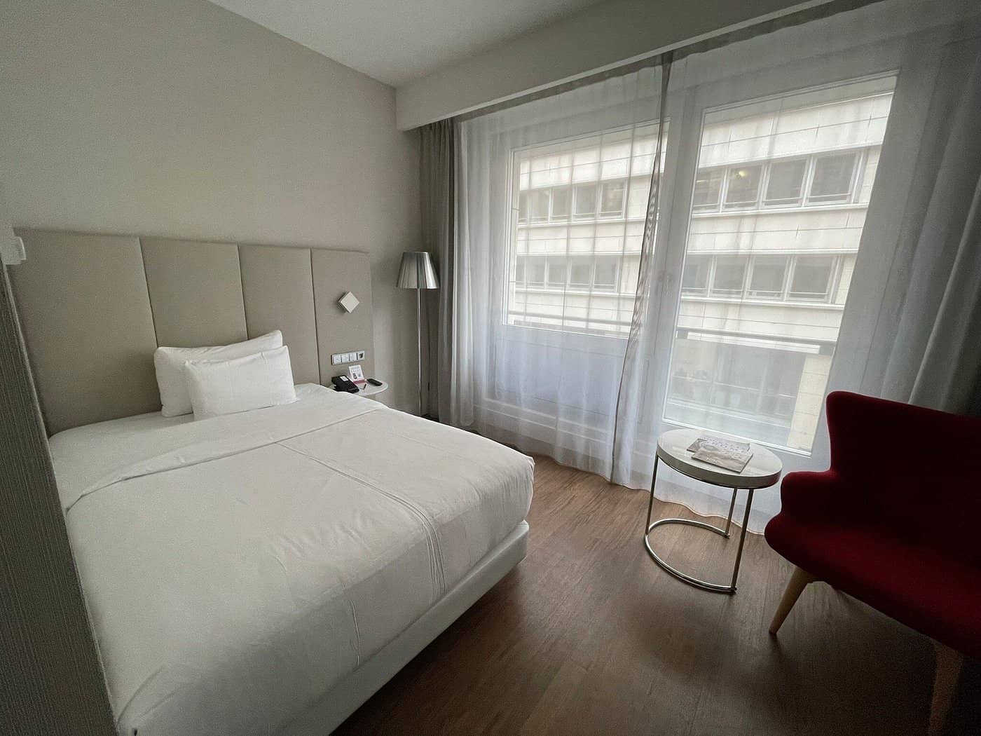 The NH Collection Berlin Mitte Friedrichstrasse features a cozy and elegant room with modern decor and a large window for natural light